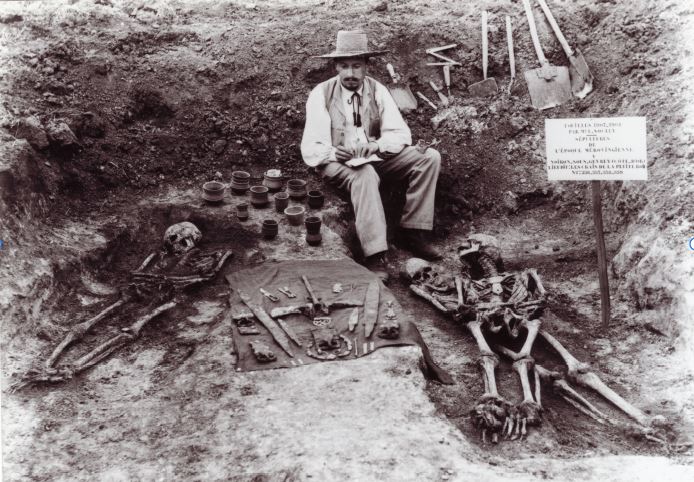 Image of an archaeologist studying skeletons in the field.