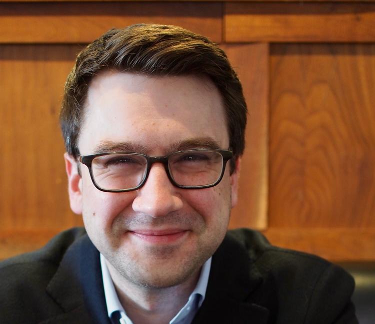 Michael Blaakman in front of a wooden wall.